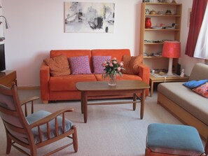 Ein Wohnzimmer mit einer Couch, Sesseln, einem Couchtisch und einem Bücherregal.
