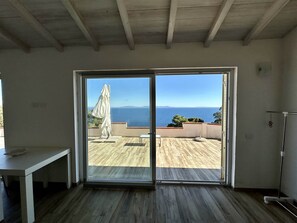 A room with a sliding glass door leading to an outdoor patio with a view of the sea. - Casa Il Porticciolo di Rio Marina (Rio Marina)