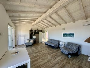 A spacious living area with wooden flooring, a white table, two patterned sofas, and a bookshelf. - Casa Il Porticciolo di Rio Marina (Rio Marina)