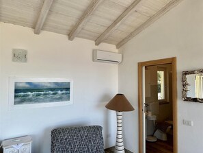 A room with a ceiling fan, an air conditioning unit, a framed picture of the ocean, a lamp, and a mirror. - Casa Il Porticciolo di Rio Marina (Rio Marina)