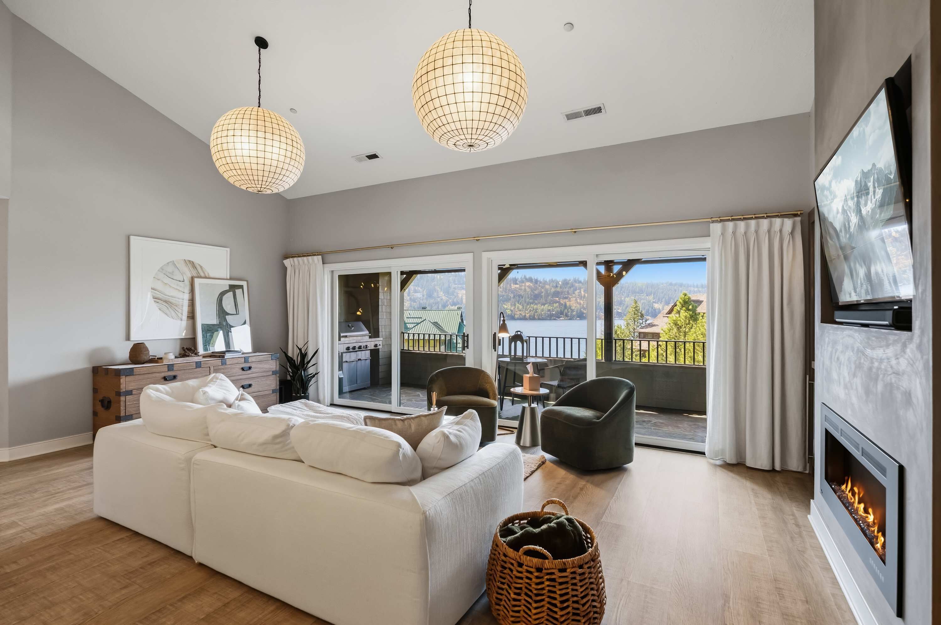A modern living room with a sofa, chairs, a fireplace, and a balcony with a scenic view.