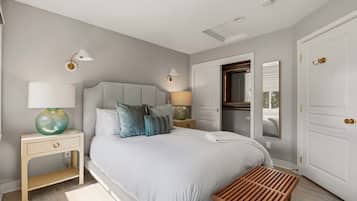 A modern bedroom with a large bed, bedside lamps, a bedside table, a bench, and a wardrobe.