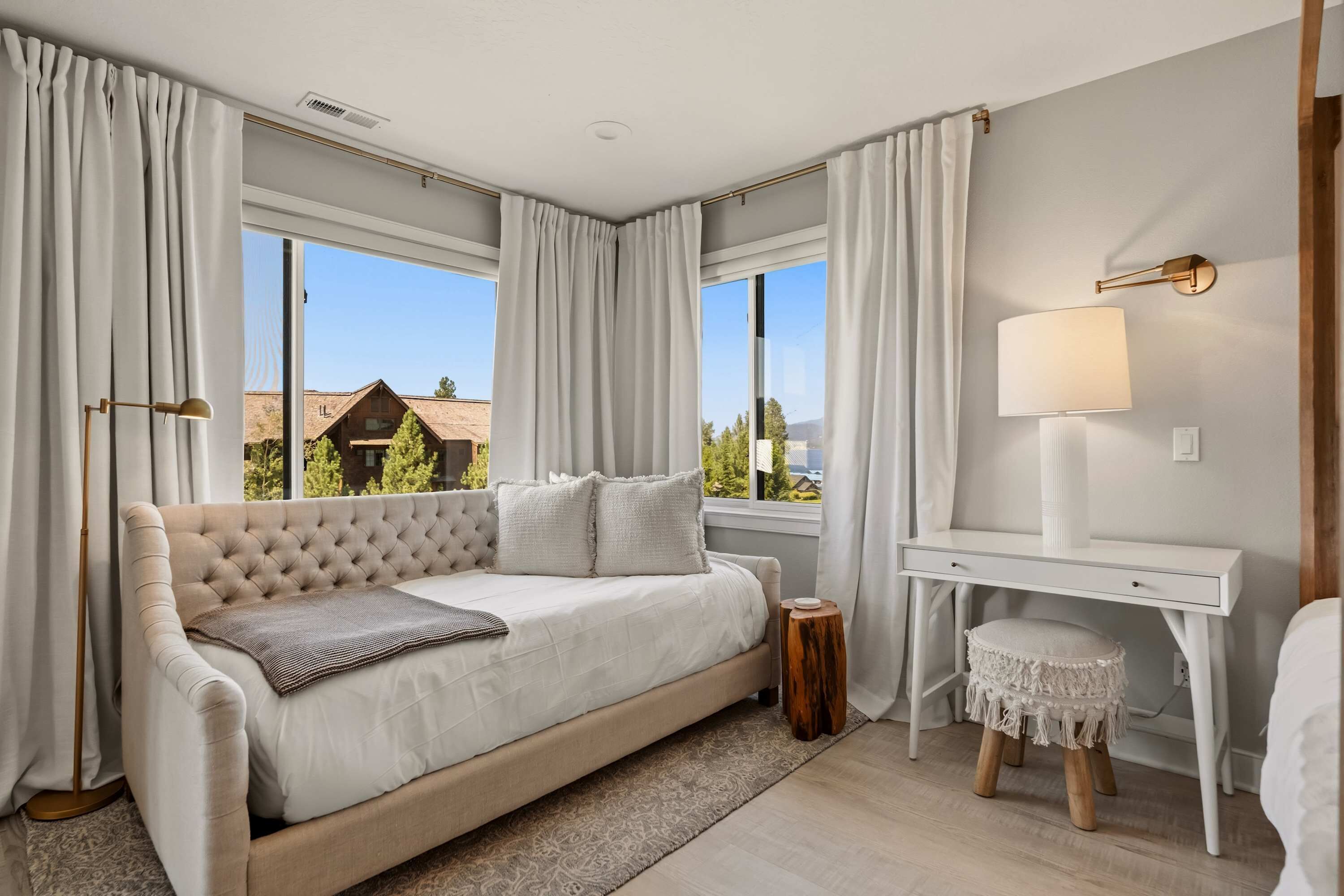 Une chambre avec un grand lit, un bureau et une vue sur les maisons à l’extérieur.