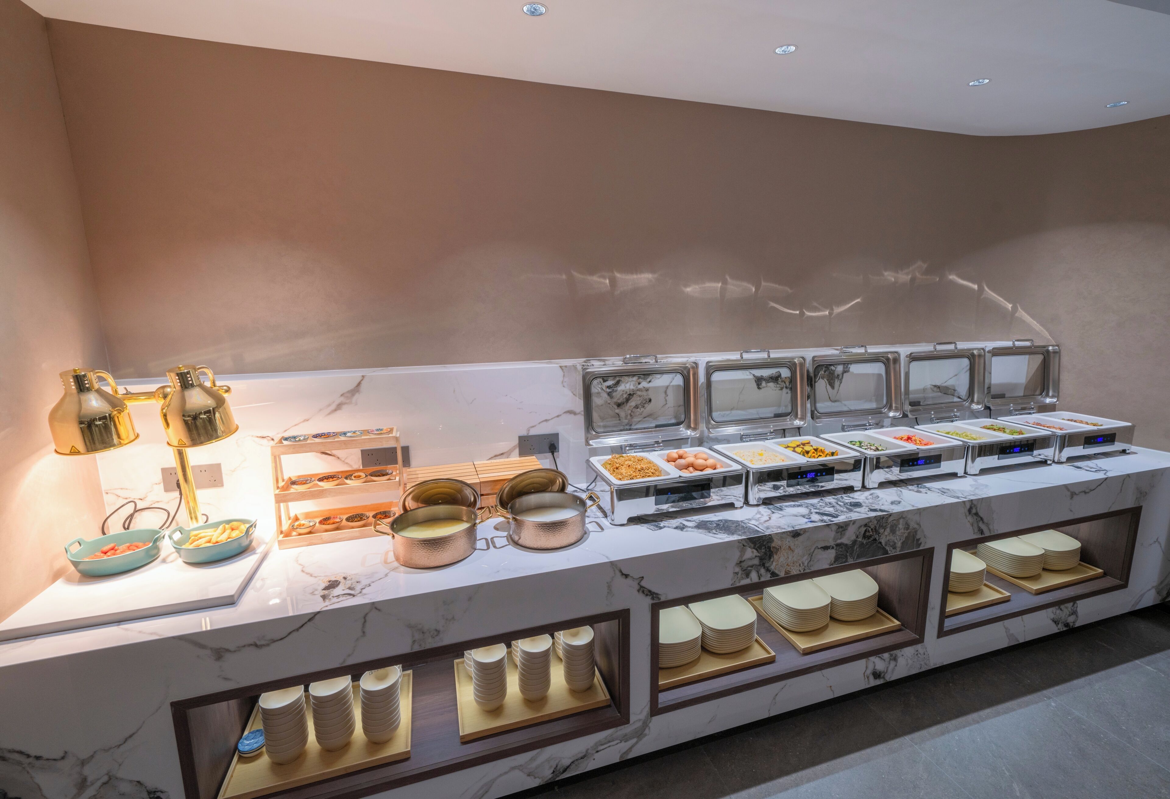 Una mesa de buffet con diferentes recipientes de comida y fuentes de servicio.