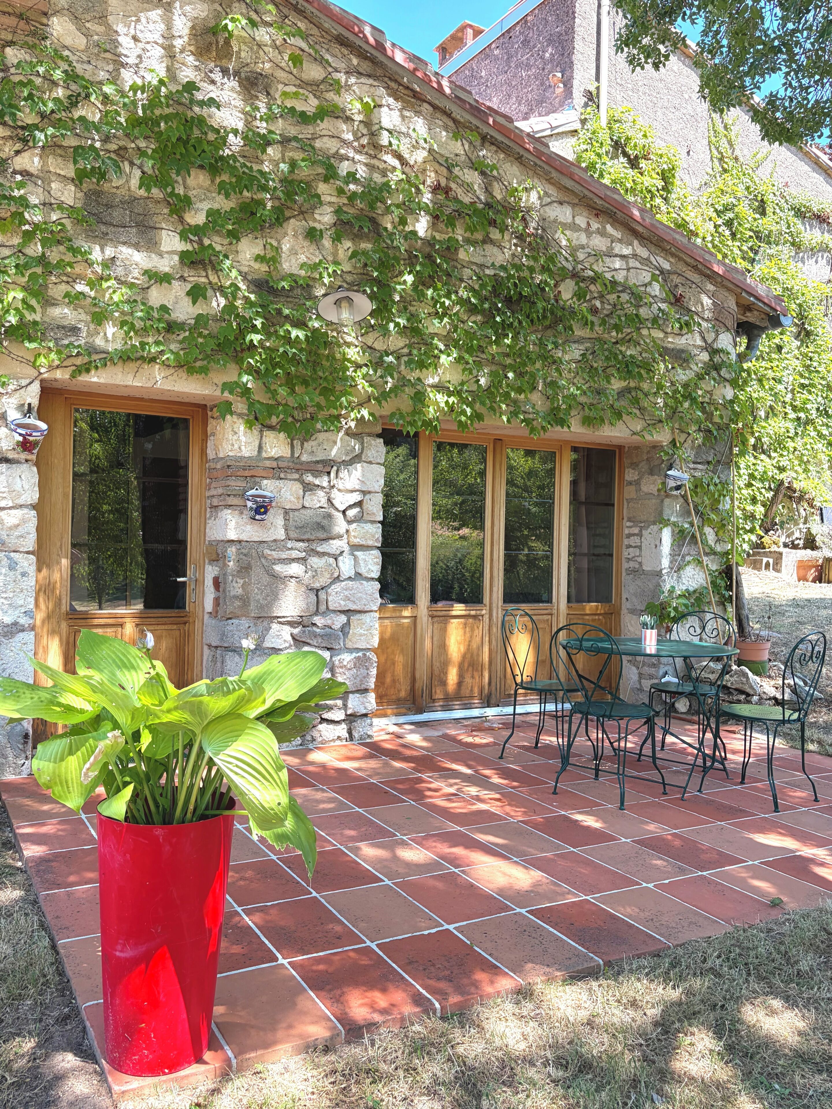 Un bâtiment en pierre doté d’un patio, d’une plante en pot et de mobilier d’extérieur.