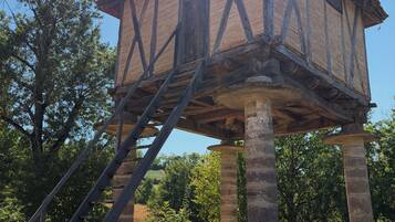 Une structure en bois en forme de tour, avec un escalier menant à son sommet, entourée d’arbres.