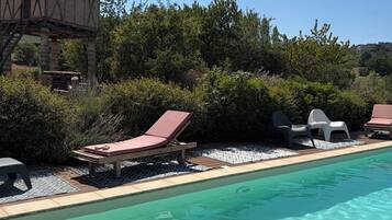 Ein klares Schwimmbecken mit Liegestühlen und einer Holzkonstruktion.