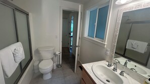 A bathroom with a toilet, sink, mirror, and a towel hanging on the wall.