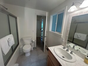 A bathroom with a toilet, sink, mirror, and a towel hanging on the wall.