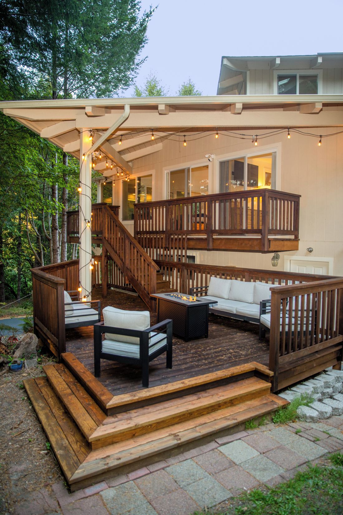 A deck with outdoor seating, a fire pit, and a staircase leading to an upper level.