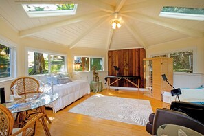 Un dormitorio con cama, escritorio, silla, piano y un ventanal grande.