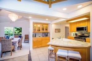 Una cocina moderna con armarios de madera, una isla grande y un comedor con sillas de mimbre.