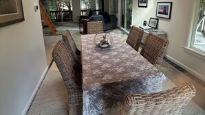 A dining area with a chandelier, wicker furniture, and a view to the outside.