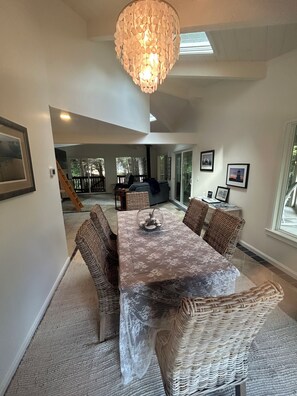 A dining area with a chandelier, wicker furniture, and a view to the outside.