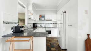 Una cocina moderna con armarios blancos, encimera negra y un salpicadero de azulejos coloridos.