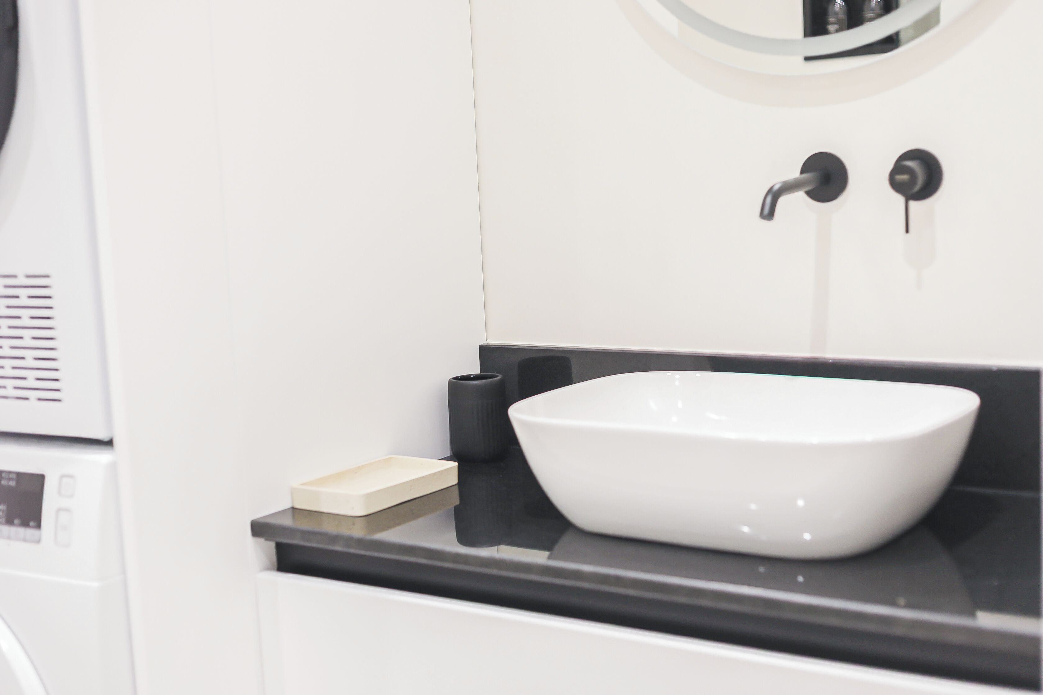 A modern bathroom with a white sink, black countertop, and a mirror above.