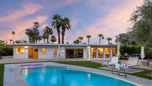 A modern house with a swimming pool, palm trees, and a patio with lounge chairs. - Mountain Mirage | MCM 3BR | Private Pool & Spa | Bocce | Sleeps 6 (Palm Springs)