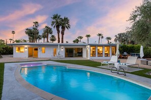 A modern house with a swimming pool, palm trees, and a patio with lounge chairs. - Mountain Mirage | MCM 3BR | Private Pool & Spa | Bocce | Sleeps 6 (Palm Springs)