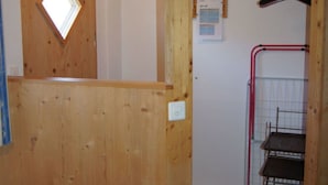 A wooden interior with a door, a hanging rack, and a radiator.