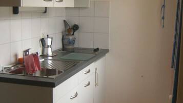 A kitchen with white cabinets, a black countertop, and a wooden ceiling.