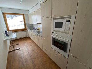 Una cocina con microondas, horno y muebles de madera.