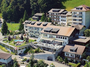 Un hotel de varios pisos con piscina en la azotea y zona de estar al aire libre.
