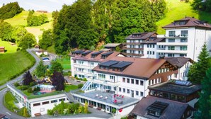 Un hotel a più piani con un cortile interno, un'area parcheggio e vegetazione circostante.