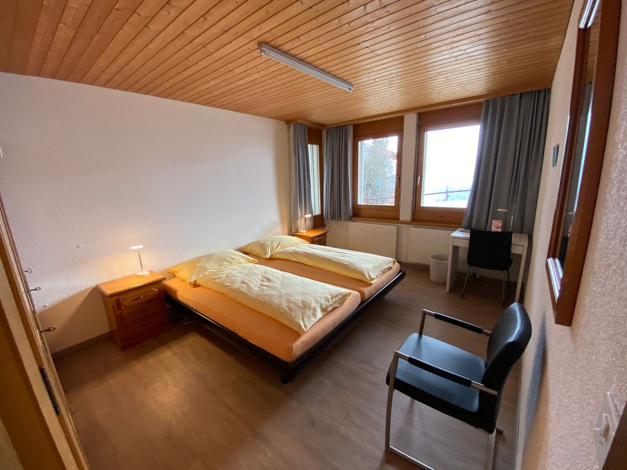 Een kamer met twee bedden, een bureau, een stoel en een raam met gordijnen.