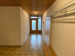 Un couloir avec un banc en bois, un radiateur et une porte dotée de panneaux en verre dépoli.