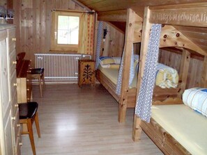 Interior de una cabaña de madera con literas, un escritorio y un radiador.