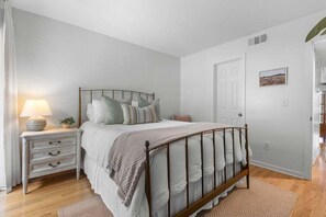 A bedroom with a bed, bedside table, lamp, and a door. - Charming 2BR/2BA Courtside Villa, near Equestrian Center and Tennis. (Seabrook Island)