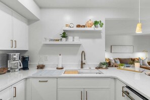 Una cocina moderna con armarios blancos, un lavamanos integrado y una cafetera.