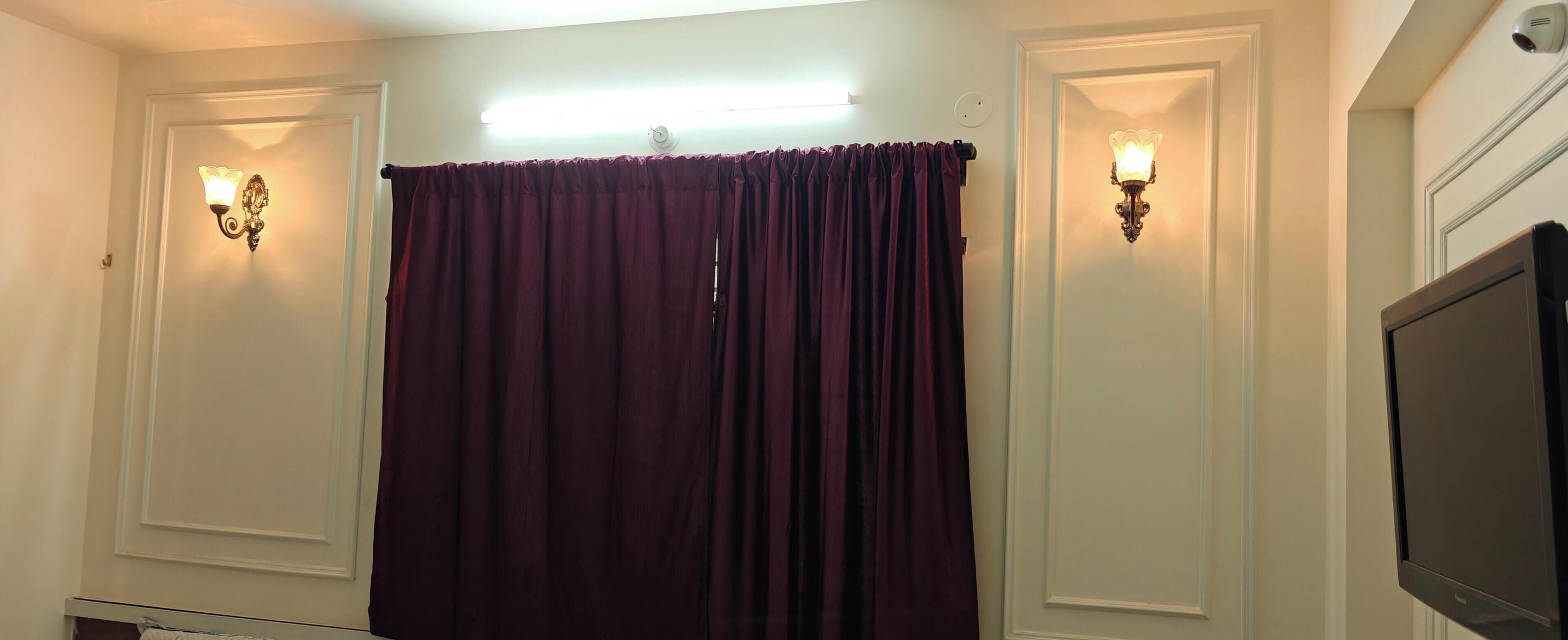 Ein Zimmer mit einem großen Fenster, einem Flachbildfernseher und zwei Wandleuchten.
