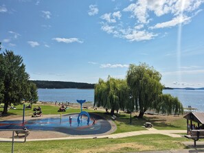 A park with a playground, benches, and a gazebo by a lake.