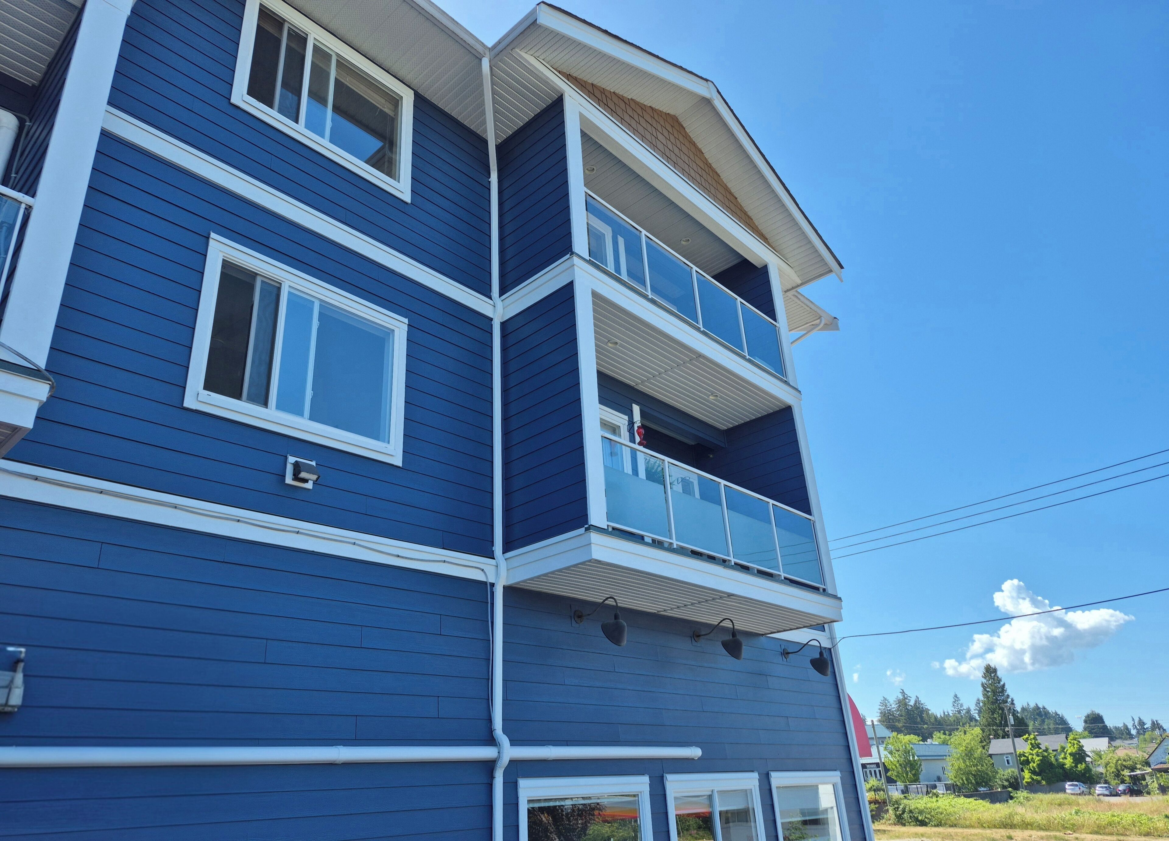 Un immeuble résidentiel à plusieurs étages, avec une façade bleue, des éléments décoratifs blancs et des balcons.