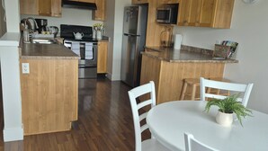 Una cocina con armarios de madera, electrodomésticos de acero inoxidable y una mesa de comedor blanca con sillas.