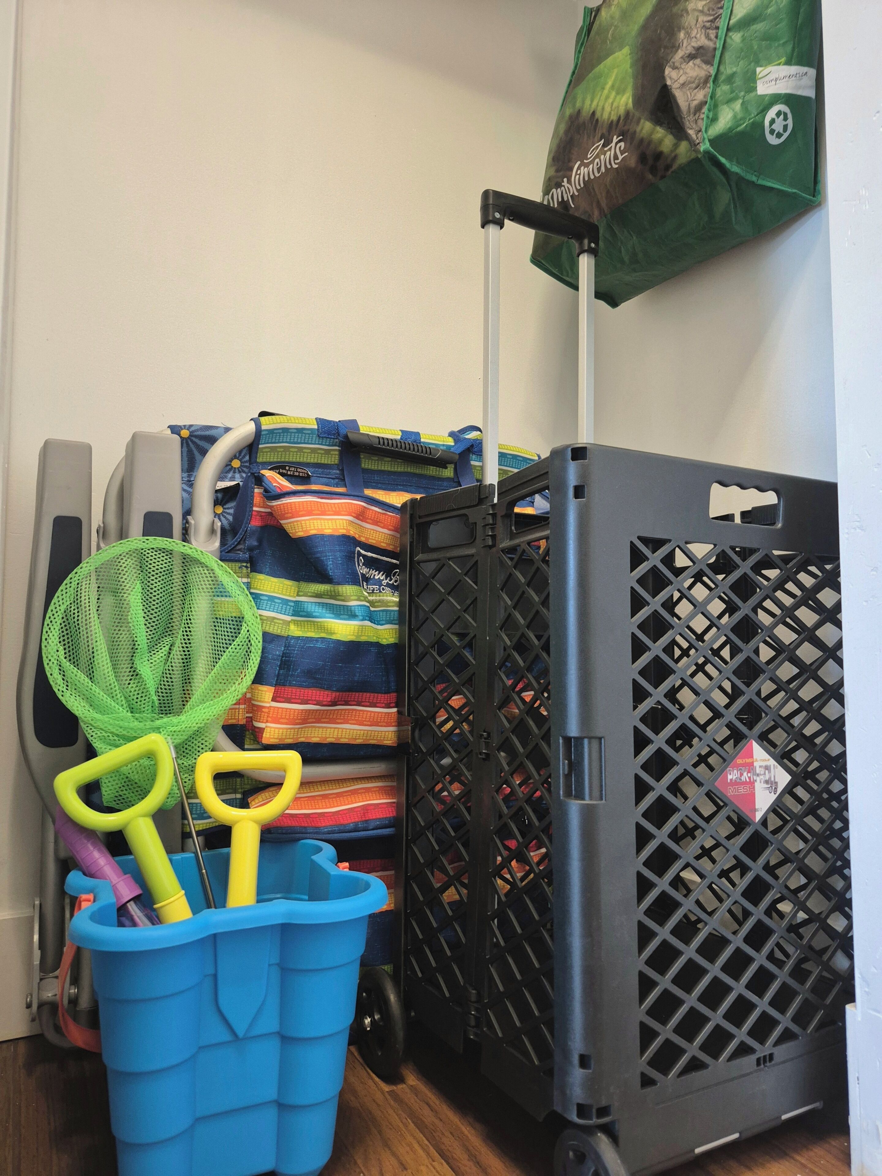 A room with a blue laundry basket, a green laundry basket, a striped bag, and a black crate.