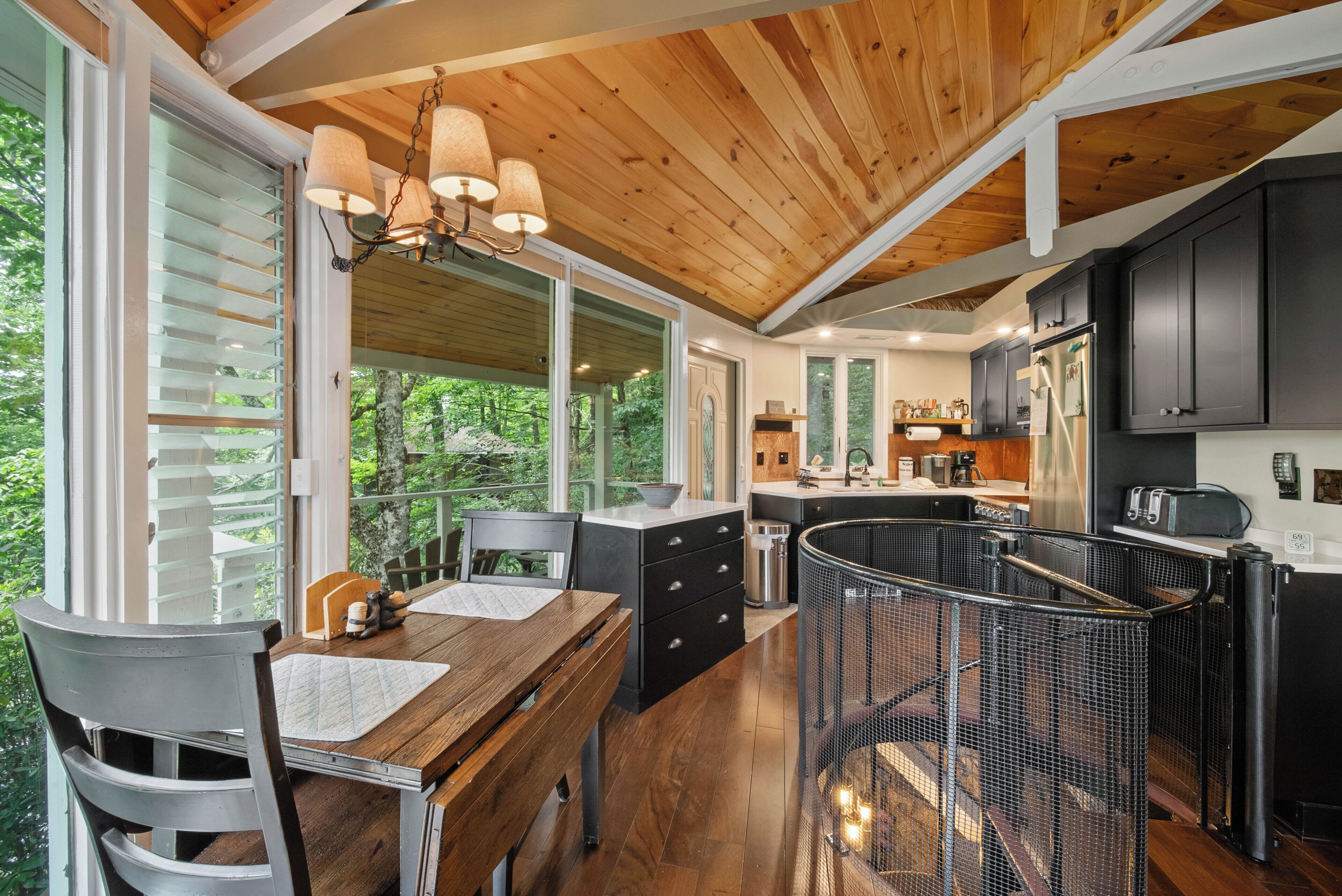A modern kitchen with wooden cabinets, a dining area with a table and chairs, and a view of the outdoors.