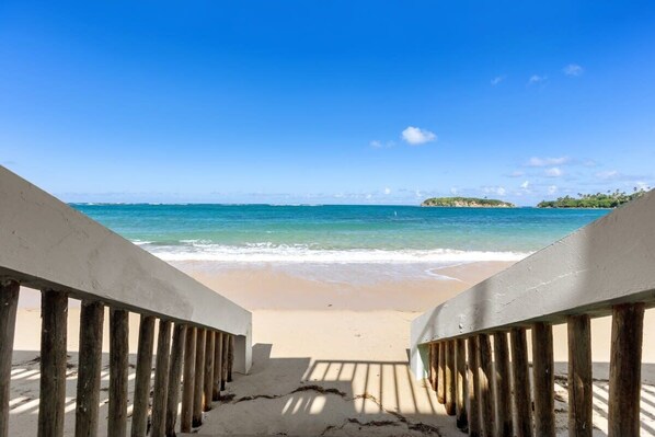 Vista a la playa con un paseo de madera que lleva a la orilla.