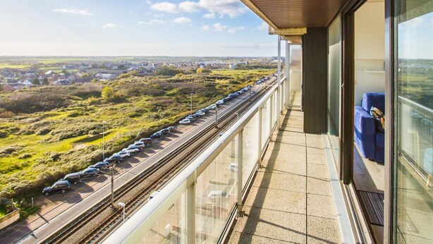 Ein Balkon mit Blick auf Gleise und die umliegende Landschaft.