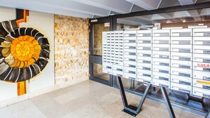 Ein modernes Interieur mit einer großen, mit nummerierten Schilderplatten gefüllten Vitrine, einer Wand mit geometrischem Muster und einem einzigartigen, runden Kunstwerk.