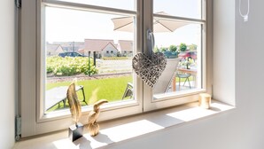 Et vindue med udsigt til en have, en metalskulptur og en hjerteformet dekoration.