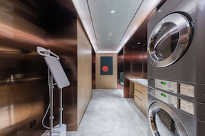 A modern bathroom with a large mirror, a washing machine, and a towel rack. - Shanghai Tangerine Expo Center Hotel (Shanghai)