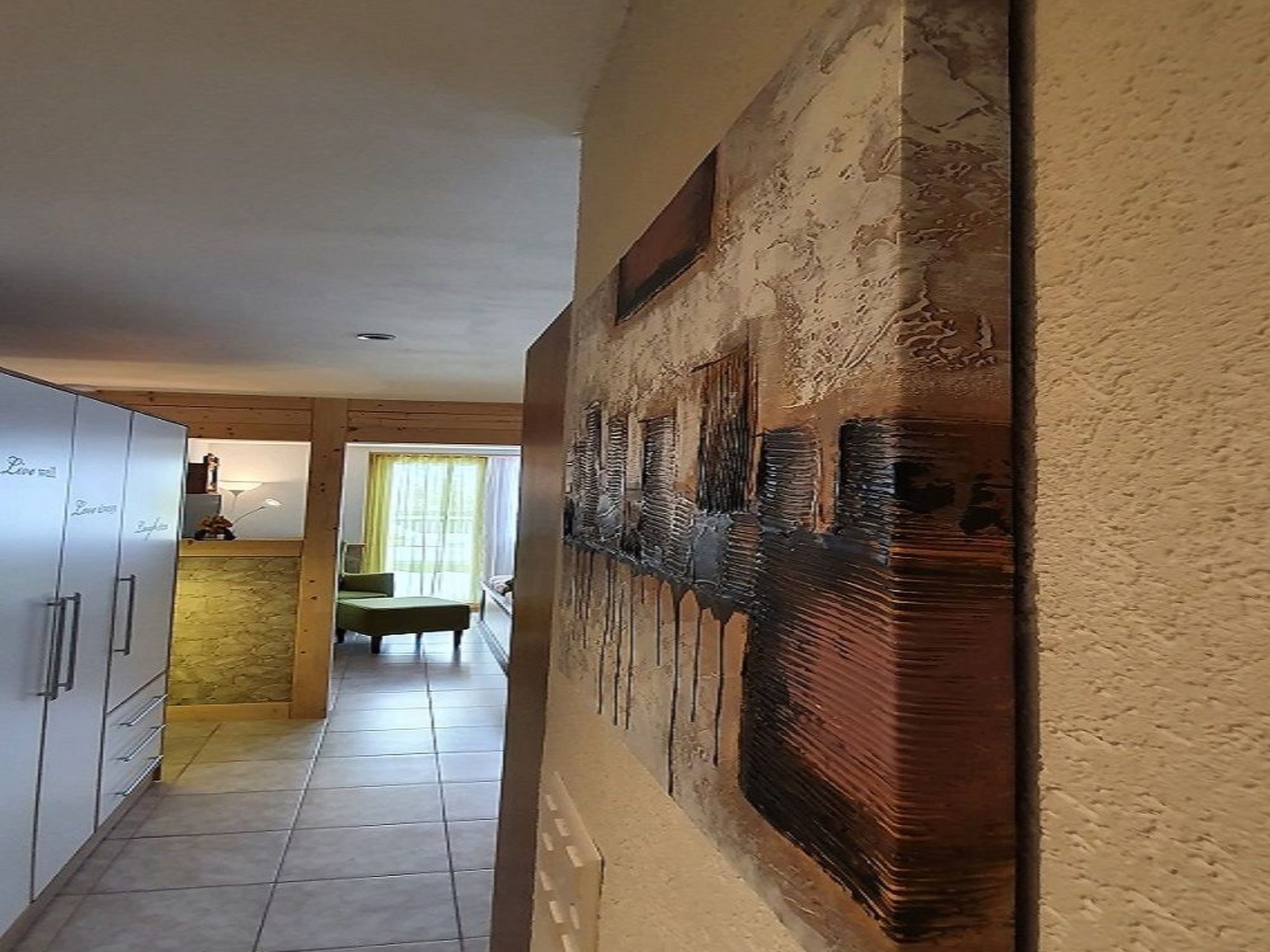 Un pasillo con comedor, cocina y un cuadro abstracto grande en la pared.