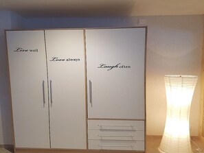 Un armario con tres puertas, cada una con una frase motivacional: 'Vive bien', 'Ama siempre' y 'Ríe a menudo'.