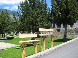 Un parque con bancos de madera y un edificio de piedra al fondo.