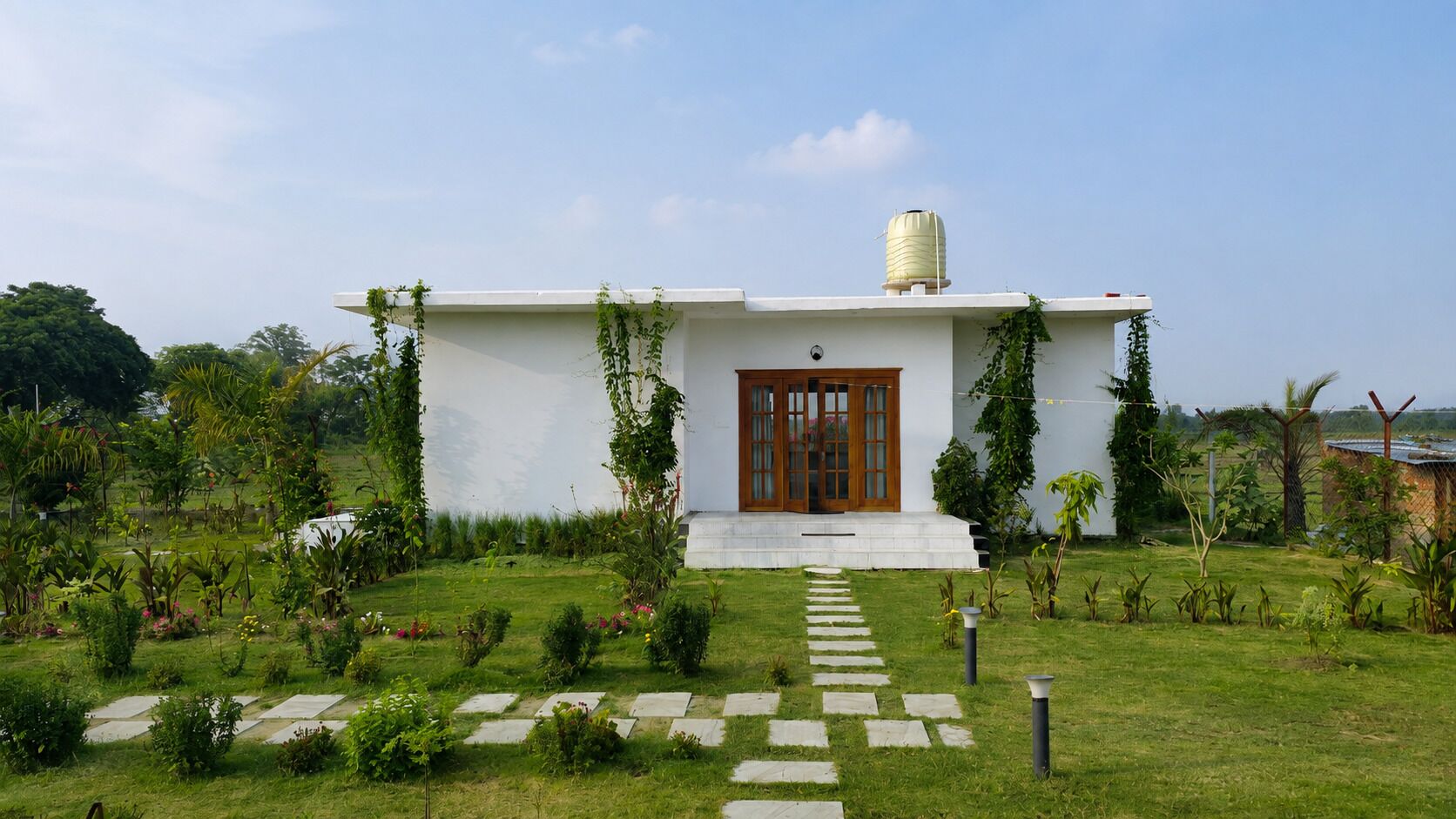 Une maison moderne avec une façade blanche, une porte en bois et un réservoir d’eau sur le toit.