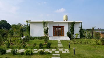 Une maison moderne avec une façade blanche, une porte en bois et un réservoir d’eau sur le toit.