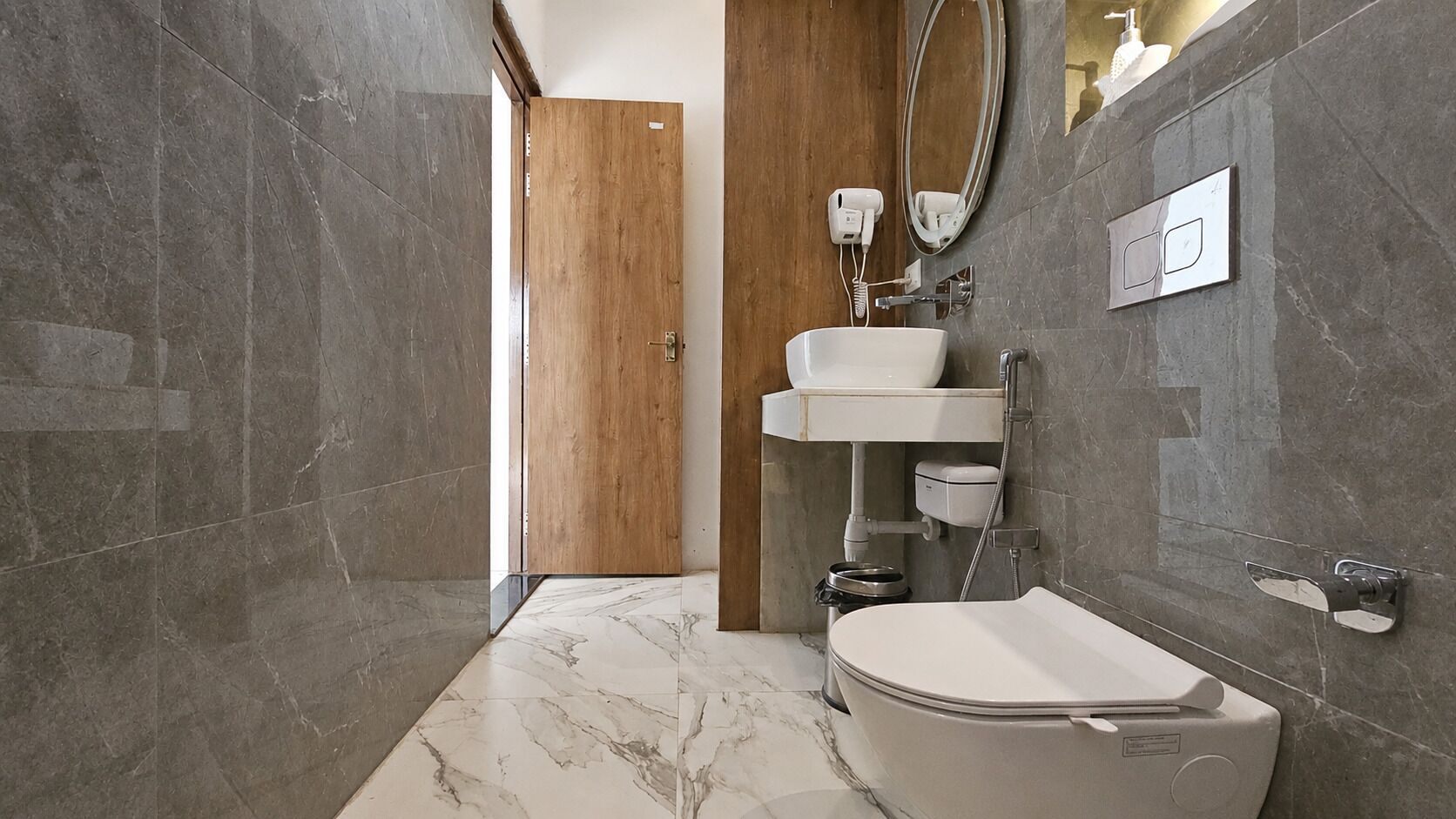 A modern bathroom with a marble floor, a white toilet, a sink, and a shower.