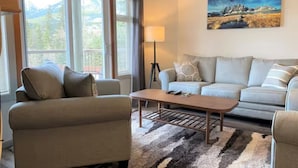 Ein Wohnzimmer mit einer Couch, einem Couchtisch und einer Lampe. Ein Gemälde ist an der Wand zu sehen.